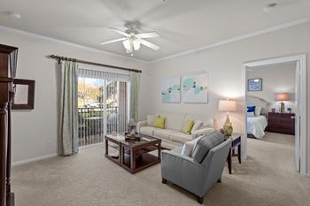 A living room with crown molding, a ceiling fan, and a sliding glass door patio.